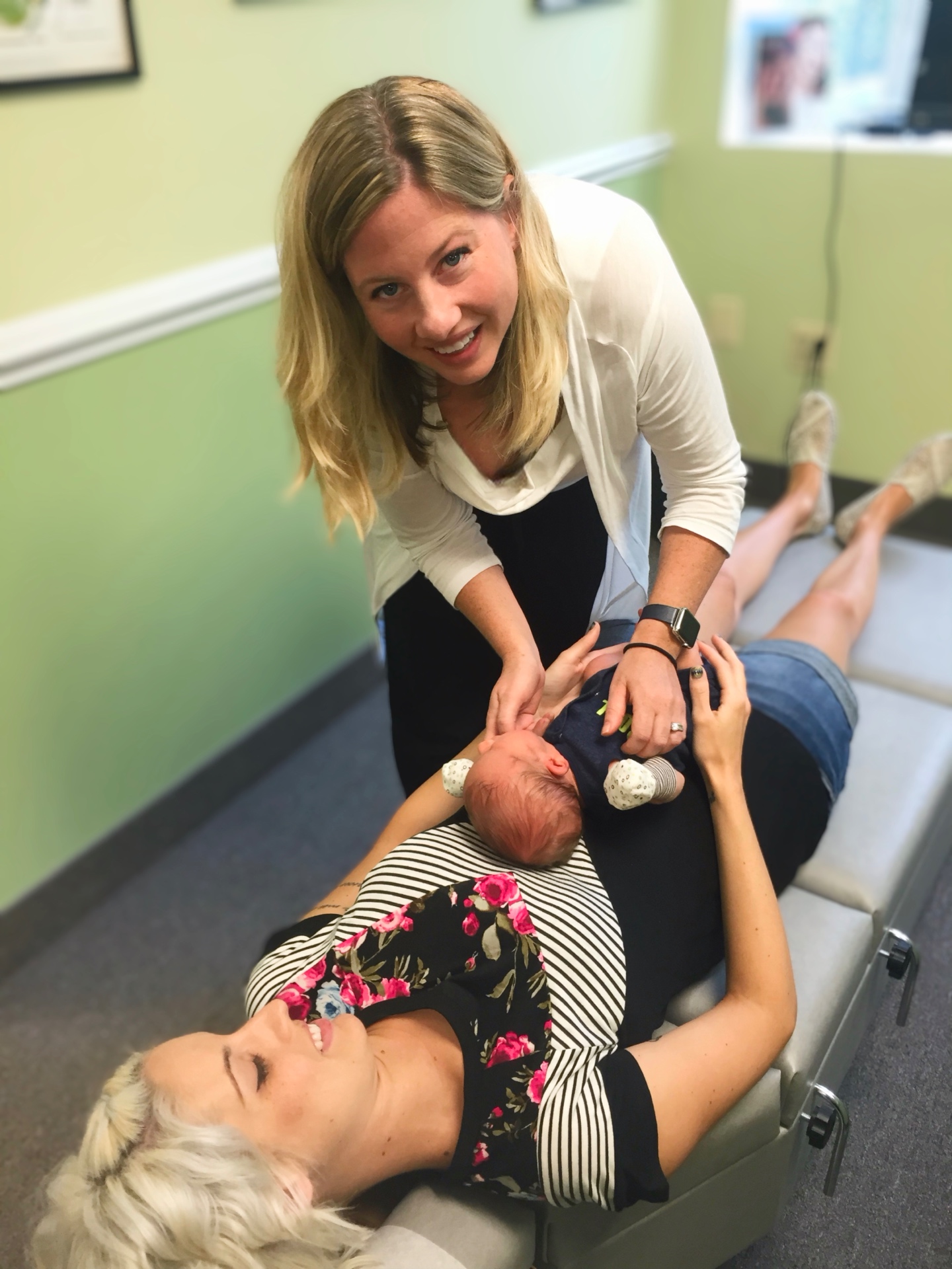 Dr. Michelle Herczeg performing a gentle pediatric adjustment with mother and baby